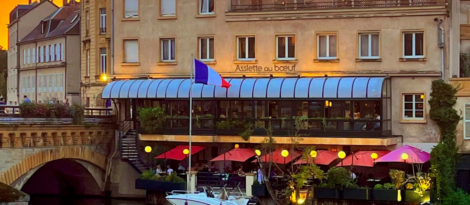 La façade de l'Assiette au bœuf éclairée au bord de la Moselle