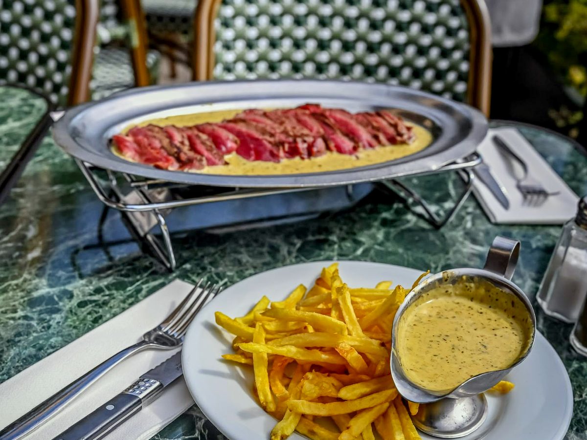 Pièce de bœuf tranchée et frites sur une table de la terrasse