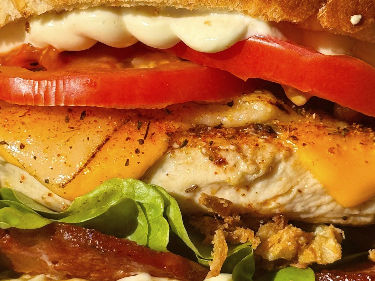 Gros plan sur un burger au poulet, cheddar et bacon